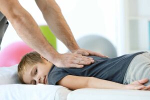 A chiropractor gently adjusts a patient's upper back while discussing stress management in a calm office setting.